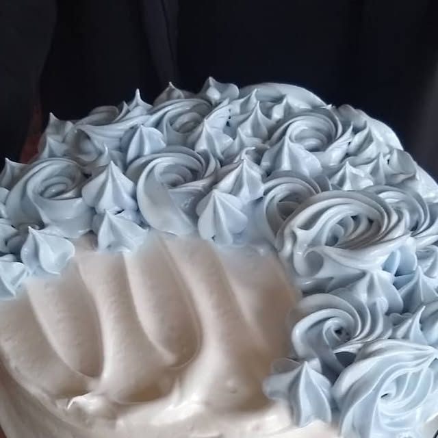 White frosted layer cake with a crown of pale blue piped rosettes